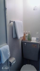 een badkamer met een toilet en handdoeken aan de muur bij Hotel Oxio in Okayama