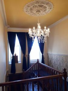 a staircase with a chandelier and blue curtains at Hallgreen castle in Inverbervie