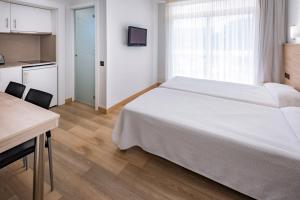 una camera con letto e tavolo e una cucina di Aparthotel Marinada a Salou