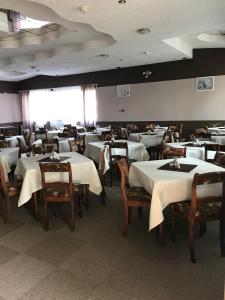 uma sala de jantar com mesas e cadeiras brancas em Hotel Holidays em Słubice