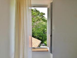 una ventana abierta con vistas a un árbol en Rooms and Studio Old Town en Rab