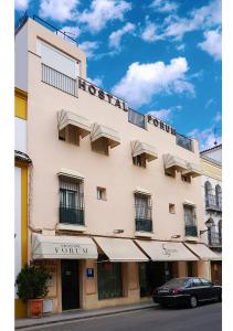 a tall white building with a car parked in front of it at Hostal Forum in Villa del Río