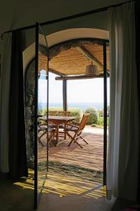 Une porte ouverte s'ouvre sur une terrasse avec une table et des chaises. dans l'établissement Dammusi I Jardina, à Pantelleria