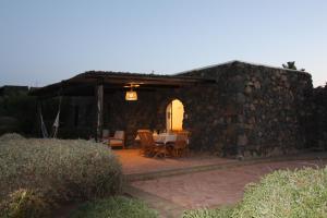 a patio with a table and a stone wall at Dammusi I Jardina in Pantelleria