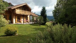 a log house with a yard and a house at Le Chalet de Philippe in La Bresse