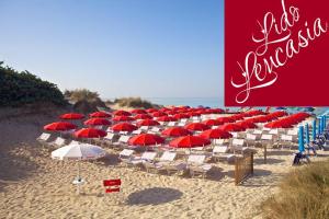 un grande gruppo di sedie e ombrelloni su una spiaggia di Hotel Intervallo a Torre Lapillo