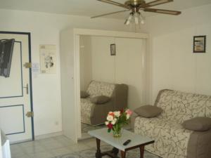 un salon avec un canapé et une table avec des fleurs dans l'établissement Le Galion, au Grau-dʼAgde