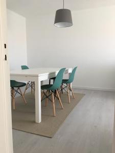 a dining room table with green chairs and a light fixture at JP House in Figueira da Foz