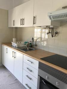a kitchen with white cabinets and a sink at JP House in Figueira da Foz