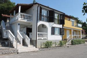 a white house with stairs and balconies on a street at Apartments Turina in Sveti Juraj