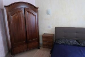 - une chambre avec une grande armoire en bois à côté d'un lit dans l'établissement S'arriali Ranch, à Iglesias