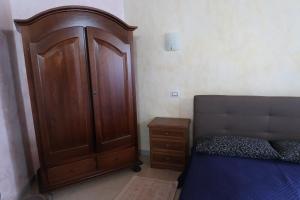 a bedroom with a large wooden cabinet next to a bed at S'arriali Ranch in Iglesias