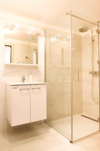 a white bathroom with a shower and a sink at Apartment Bugenvilija in Lovran