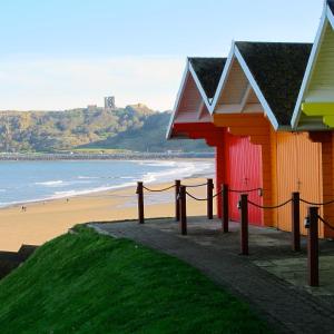 a beach with a red and yellow building and the ocean at Atlanta Hotel in Scarborough