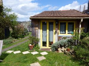 uma pequena casa com portas amarelas num quintal em La Maison Rouge em Chauvigny
