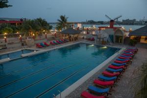 ein großes Schwimmbecken mit Stühlen und einer Windmühle in der Unterkunft Hotel Du Lac in Cotonou