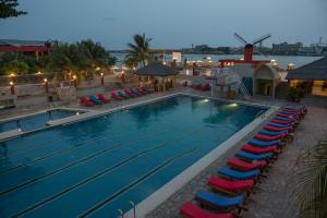 a large swimming pool with chairs and a windmill at Hotel Du Lac in Cotonou