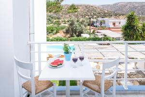 een witte tafel met twee glazen wijn op een balkon bij Marina Hotel in Matala