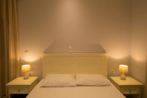 a bedroom with a white bed with two lamps on it at Mare Studios Exclusive in Plomarion