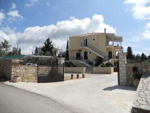 una casa con una valla de piedra y un camino de entrada en Kalliope Apartments, en Tsoukaladhes