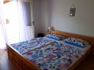 a bed with a colorful comforter in a bedroom at apartman Sanja in Rab