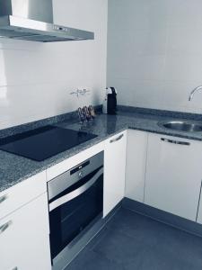 biała kuchnia ze zlewem i kuchenką w obiekcie Apartamento Cánovas w mieście Tarifa