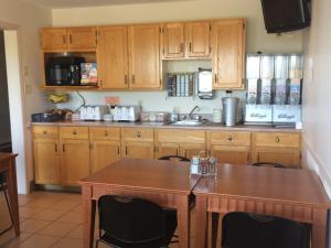 a kitchen with wooden cabinets and a wooden table at Coastal Inn Sackville in Sackville