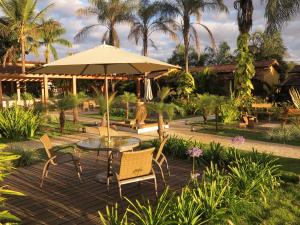 a patio with a table and chairs and an umbrella at Pousada Recanto da Grande Paz in Alto Paraíso de Goiás