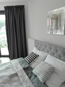 a bedroom with a bed with a gray headboard and pillows at Apartament Horyzont 405 Międzyzdroje in Międzyzdroje
