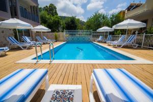 a swimming pool on a wooden deck with chairs and umbrellas at Kelebek Hotel in Kalkan