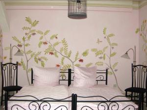 a bedroom with a bed with a tree mural on the wall at Pension Casa Luciko in Brachwitz