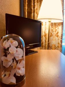 un frasco de cristal con flores en una mesa frente a una TV en Hotel Zvezdny, en San Petersburgo