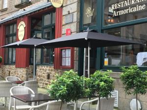 two tables and chairs with umbrellas in front of a restaurant at Hotel Brasserie Armoricaine in Saint Malo