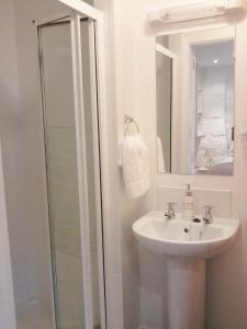 uma casa de banho branca com um lavatório e um chuveiro em Finn MacCools Public House & Guest Inn em Bushmills