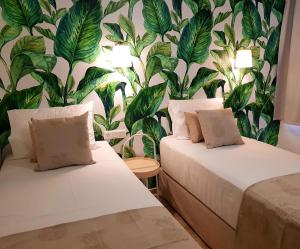two beds in a room with a tropical wallpaper at Nissos Home in Hersonissos