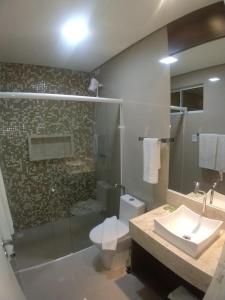 a bathroom with a shower and a toilet and a sink at Premium Hotel in Mombaça