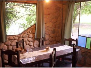 una mesa y sillas en una habitación con una pared de piedra en Cabanas Las Achiras en San Javier