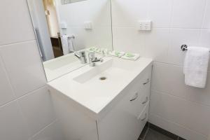 Baño blanco con lavabo y espejo en Seven Pines Motor Inn, en Mildura