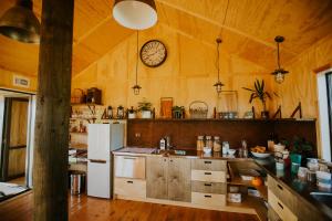 a kitchen with a white refrigerator and a clock on the wall at Valley Views Glamping in Kurow