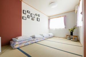 een woonkamer met een lange bank op de vloer bij ABC Guest House in Izumi-Sano