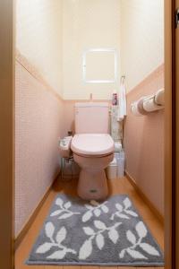 a small bathroom with a toilet and a rug at ABC Guest House in Izumi-Sano