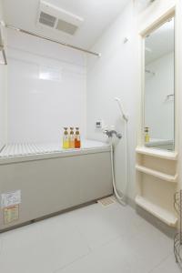 a white bathroom with bottles on a shelf at ABC Guest House in Izumi-Sano