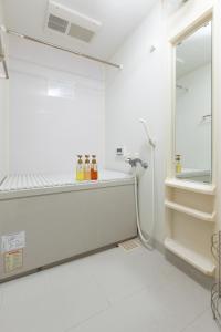 泉佐野市にあるABC ゲストハウスの白いバスルーム(棚にボトル付)