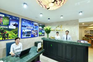 three people standing at a counter with a laptop at Hanoi Amorita Boutique Hotel & Travel in Hanoi