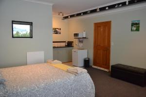 a bedroom with a bed and a small kitchen at Treetops B&B in Portobello