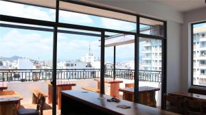 a room with a large window with tables and chairs at Bondi Backpackers Nhatrang in Nha Trang