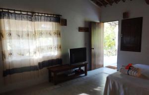 a living room with a television and a window at Pousada Infinito Mar in São Miguel dos Milagres