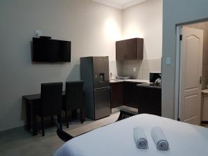 a kitchen with a table and chairs and a refrigerator at Private Apartments & Biz Stays Pretoria in Pretoria