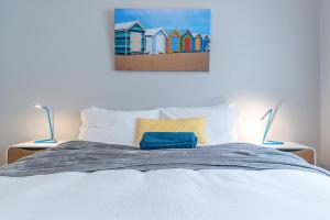 雪梨的住宿－海灘度假公寓，一张带两盏灯的床和一幅海滩房屋画