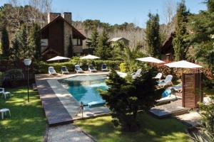 uma piscina com cadeiras e guarda-sóis num quintal em Cabañas del Bosque em Mar Azul